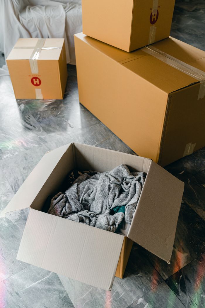 about-04 From above of cardboard boxes with packed items placed on floor in new apartment